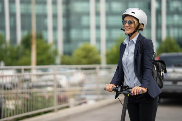 One mature businesswoman commuting to work on the electric scooter in the city on sunny day