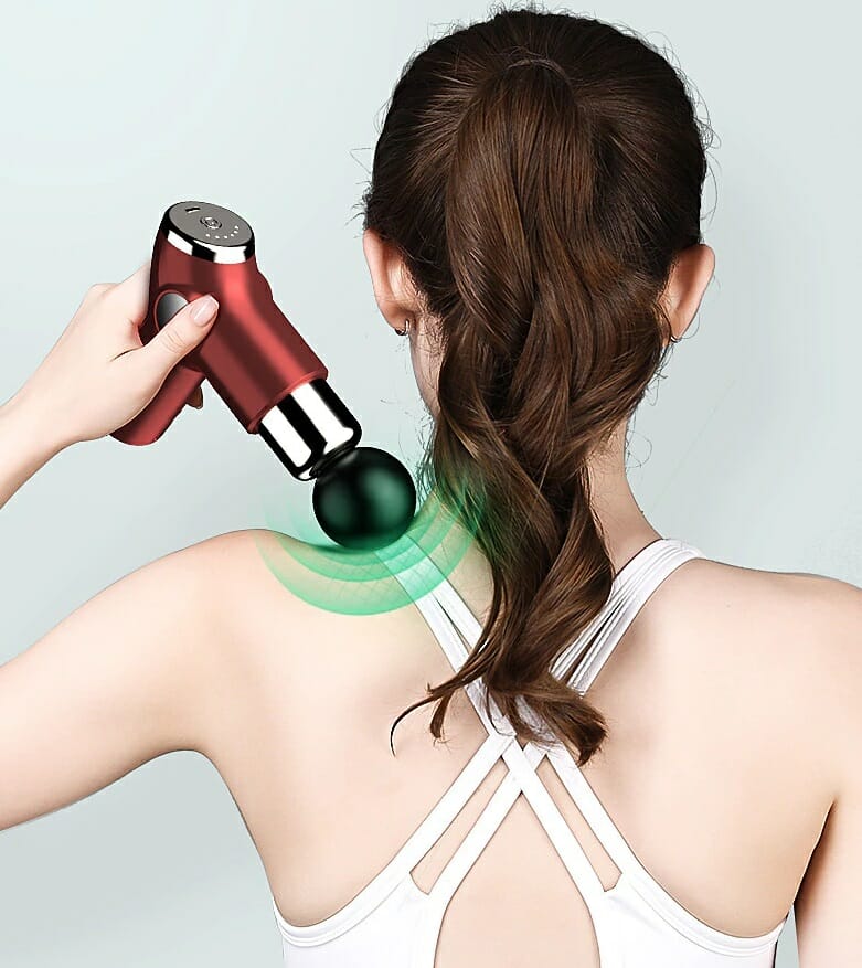 A woman is using an electric massager on her back.