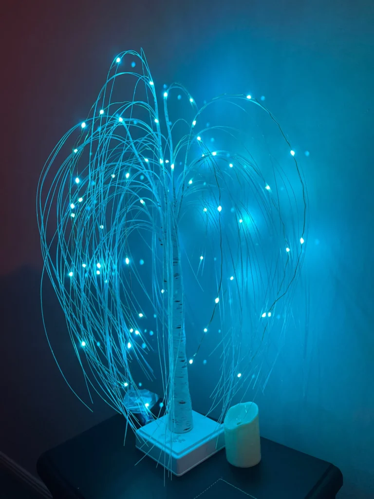 A blue LED tree on a table in a dark room, creating a mesmerizing atmosphere with its ethereal fairy lights.